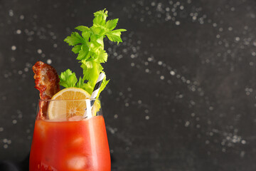 Glass of bloody mary cocktail with bacon, celery and lemon on black background, closeup