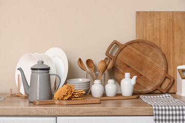 Teapot with tasty waffles and utensils on table in kitchen