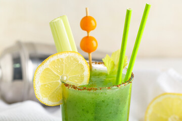 Glass of green bloody mary cocktail garnished with physalis berries and lemon on white background,...