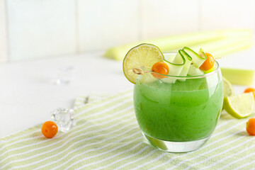 Glass of green bloody mary cocktail garnished with physalis berries, lime and cucumber slice on...