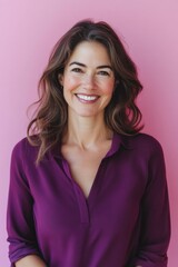 Fototapeta premium A confident and happy woman in a purple blouse against a pink background, suitable for business or professional use.