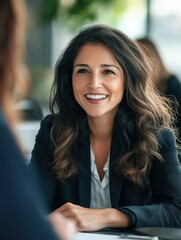 Fototapeta premium A professional woman in business attire smiling during a meeting or interview, suggesting a positive work environment.