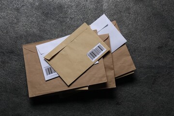 Stack of different paper envelopes on dark grey table, top view. Post office