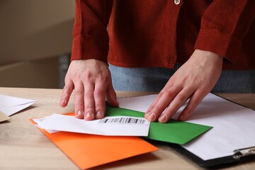 Woman putting barcodes onto envelopes at table in post office, closeup