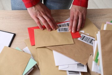Woman putting barcodes onto envelopes at table in post office, above view