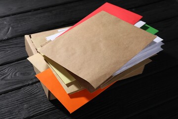 Different paper envelopes and parcel on black wooden table, closeup. Post office