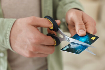 Man cutting his credit card indoors, closeup