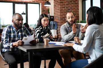 Black female applicant sits in a formal interview with diverse recruiters at office desk. Asian...