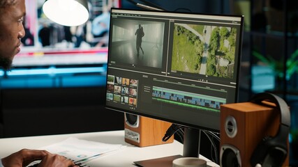 Male video editor working on creative software to create montage, using color correction and adding...
