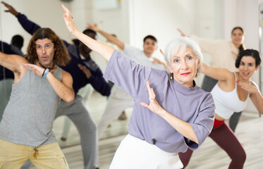 Group of adult people practices dance aerobics in class in the dance studio