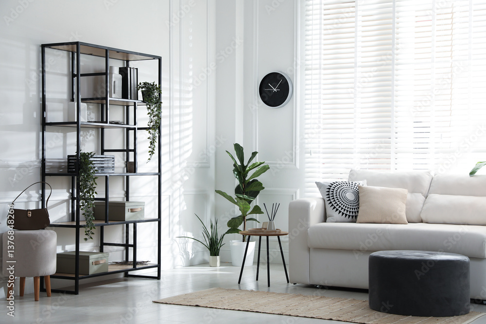 Poster stylish shelving unit with decor and sofa in room