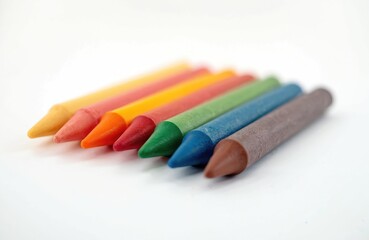 Fototapeta premium Colorful wax crayons set against white background. Variety of colors for art projects, drawing, school. Childhood fun, creativity, education. Symbol of creative expression, artistic tools,