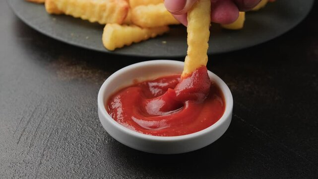Dipping Homemade Crinkle Cut French Fries in a ketchup