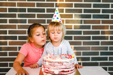Children blowing candles on birthday cake together