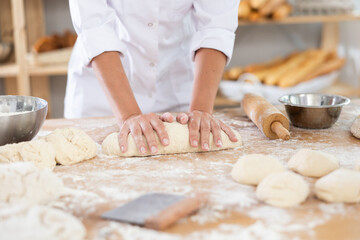 Chef working with dough in a bakery, surrounded by flour and bread-making tools, creating artisanal bread.