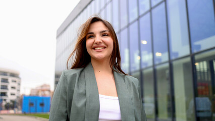 Young businesswoman smiling and walking near office building