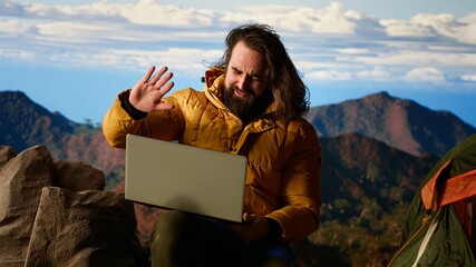 Mountain adventurer prioritizes his online business over safety, working on his laptop despite the...