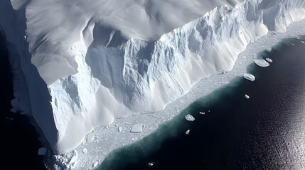 Obraz premium An aerial view showcases a massive Antarctic ice cliff dramatically meeting dark ocean waters with scattered icebergs.