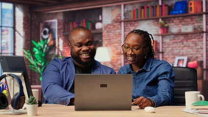 Black freelancing couple doing a high five to celebrate their achievement, completing tasks to...