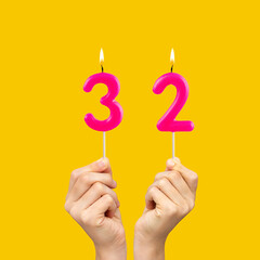 Birthday number 32 - Hands holding fuchsia colored candles