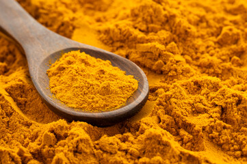 Organic turmeric powder in a wooden spoon - Curcuma longa
