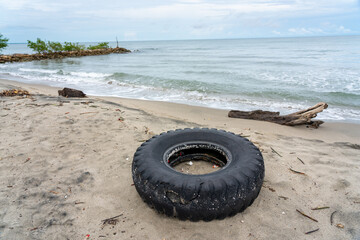 Truck tire with tree trunks abandoned on a beach on the Colombian coast.