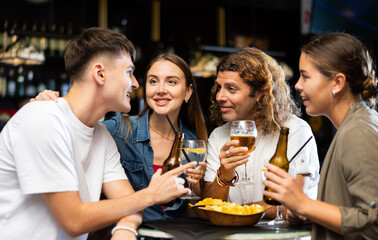 Group of happy friends enjoying beer, crisps and talks in the evening pub