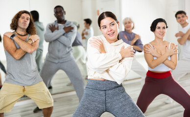 Obraz premium Cheerful sporty young girl having fun and dancing hip hop during workout in group dance class for adults