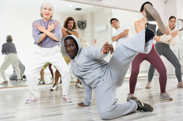 Obraz premium African-american man rehearsing modern hip-hop with group in dance school
