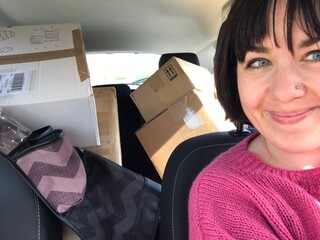 UGC woman smiling during selfie in car surrounded by webshop boxes
