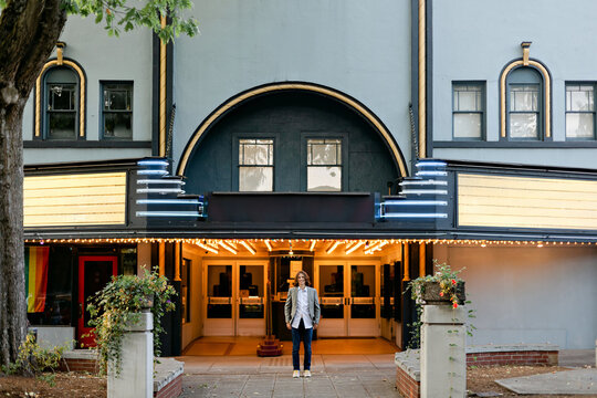 Teenage Boy Standing in front of Theater in Hometown