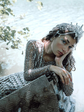 Woman in Tiara and Glittering Dress Resting by the Water