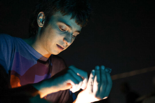 Young man cutting weed manually to make a joint in low light