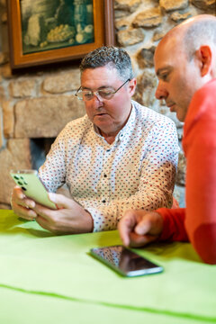 Two men using smartphones in a restaurant are comparing something