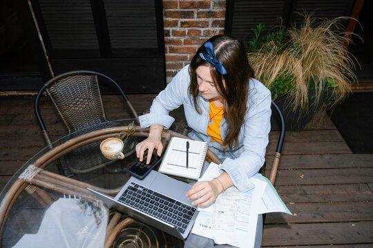 A woman is working sitting on a cafe terrace