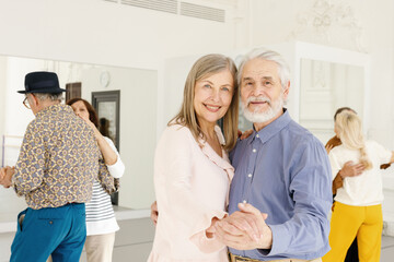 Retired couple posing for photo while dancing at group dance class