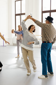 Pair of retirees executing dance move at group class in ballroom