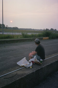 Traveling Man Sits Next to Food by the Road