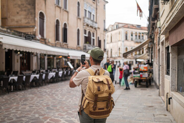 Tourist taking a photo with his phone at a restaurant on a street
