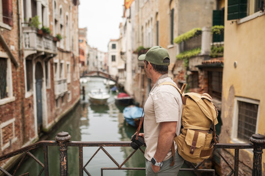 Tourist on a bridge over a canal in Venice, watching the boats go by