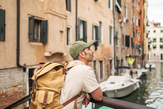 Tourist on a bridge over a canal in Venice, watching the boats go by