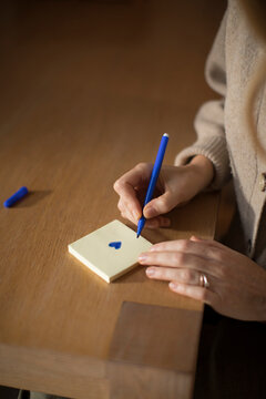 Woman Drawing a Blue Heart on a Post-it