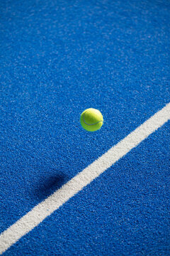 Padel Ball in Mid-Air Above the White Line on a Blue Padel Court

