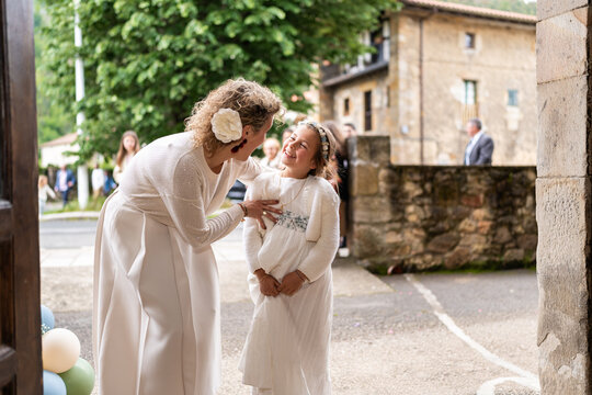 Woman congratulating smiling girl celebrating her first communion