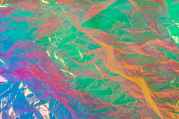 Holographic crumpled surface of neon pink, blue and green tones