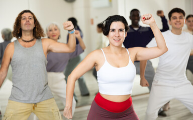 Cheerful sporty young Hispanic woman having fun and dancing hip hop during workout in group dance class for adults