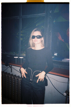 Person in stylish outfit poses confidently in a dimly lit venue