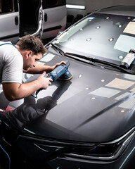 Hombre puliendo pintura de automovil con pulidora y pasta de pulir para dar brillo