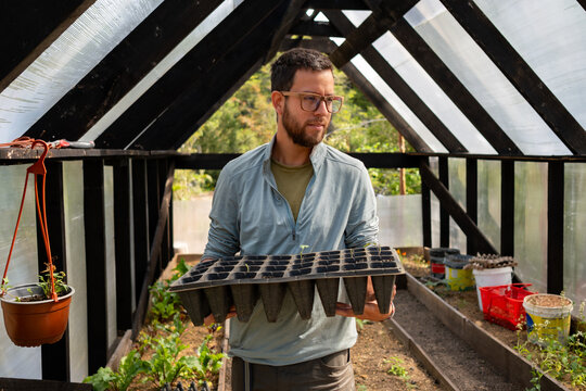Gardener Preparing Seedlings in Sunlit Greenhouse
