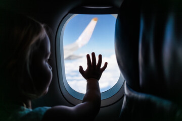 Girl touching window and looking at sky in airplane